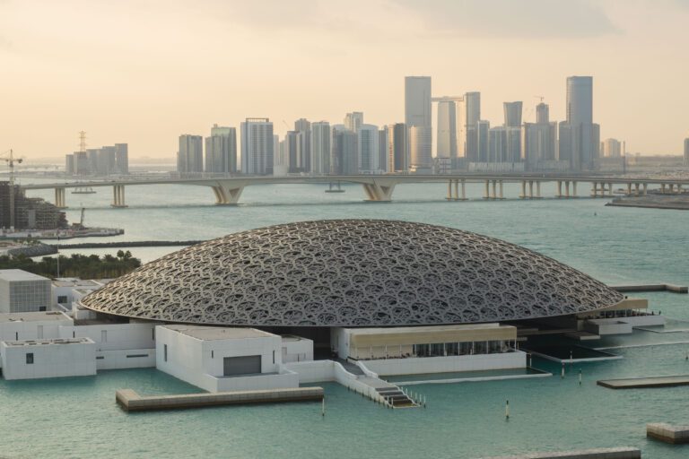 A large white dome with a geometric pattern sits on top of a turquoise body of water